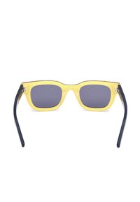 Gafas de sol de plástico amarillo con lentes cuadradas, lentes tintados en gris oscuro y patillas de color azul oscuro a juego. Diseño simple y contemporáneo.