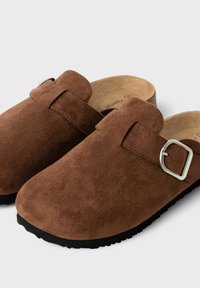 Ruske suede klumpere med rund tå, justerbar spænde rem og sort gummisål. Blød tekstur og minimalistisk design.