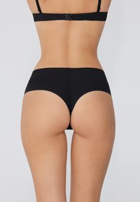 Zwarte high-waisted onderbroeken met een gladde textuur en een gebogen achterkantontwerp, die minimale bedekking bieden. Eenvoudige en naadloze constructie.