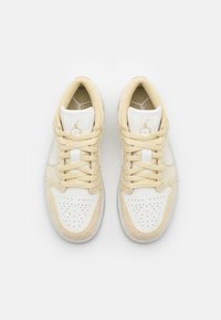 Baskets beige et blanches avec une tige en cuir et suède. Présentent une boîte à orteils perforée, des lacets crème et un logo doré sur la languette.