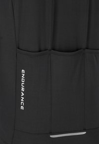 Black fabric panel with three vertical stitched pockets and "ENDURANCE" printed in white vertically on the left pocket.