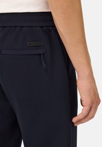 Pantalones jogger en color marino con cintura ajustable, cuentan con un bolsillo lateral, parche con el logo de BTECH y una textura suave y lisa.