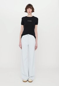 Black short-sleeve t-shirt with "MAX&Co" logo, paired with light blue wide-leg jeans. Off-white shoes complete the outfit.