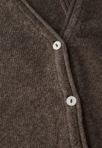 Brun stickad cardigan med V-ringning, texturerat tyg och två runda vita knappar för stängning.