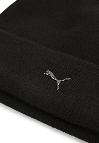 Black knit beanie with a soft texture, featuring a metallic silver Puma logo on the folded edge. Simple, unembellished design.