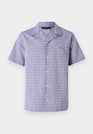 Camicia a maniche corte in tessuto viola chiaro con un motivo geometrico, dotata di colletto classico e chiusura con bottoni, completata da dettagli distintivi del logo.