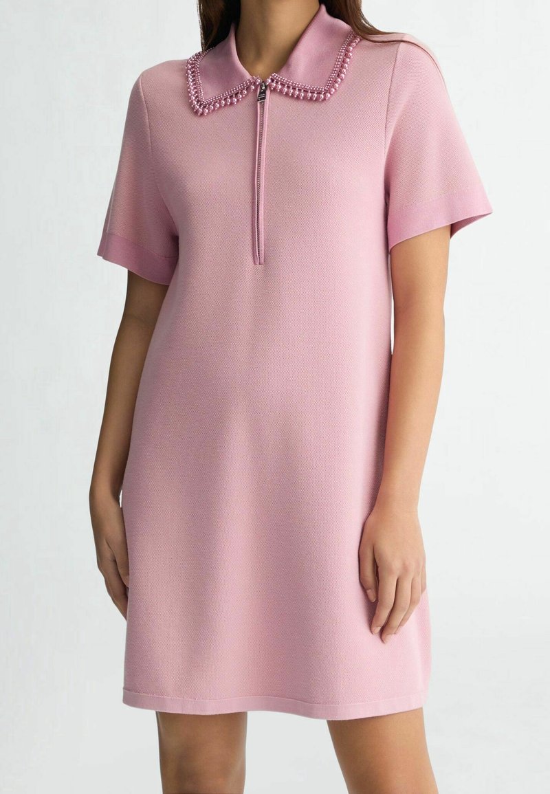 Robe polo rose à manches courtes, en tissu texturé, avec un col zippé et des détails de col en perles pour un intérêt supplémentaire.