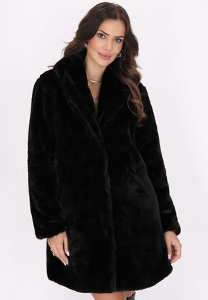 Cappotto in pelliccia sintetica nera con ampio colletto, maniche lunghe e una consistenza morbida. Presenta una vestibilità rilassata e nessuna chiusura visibile.