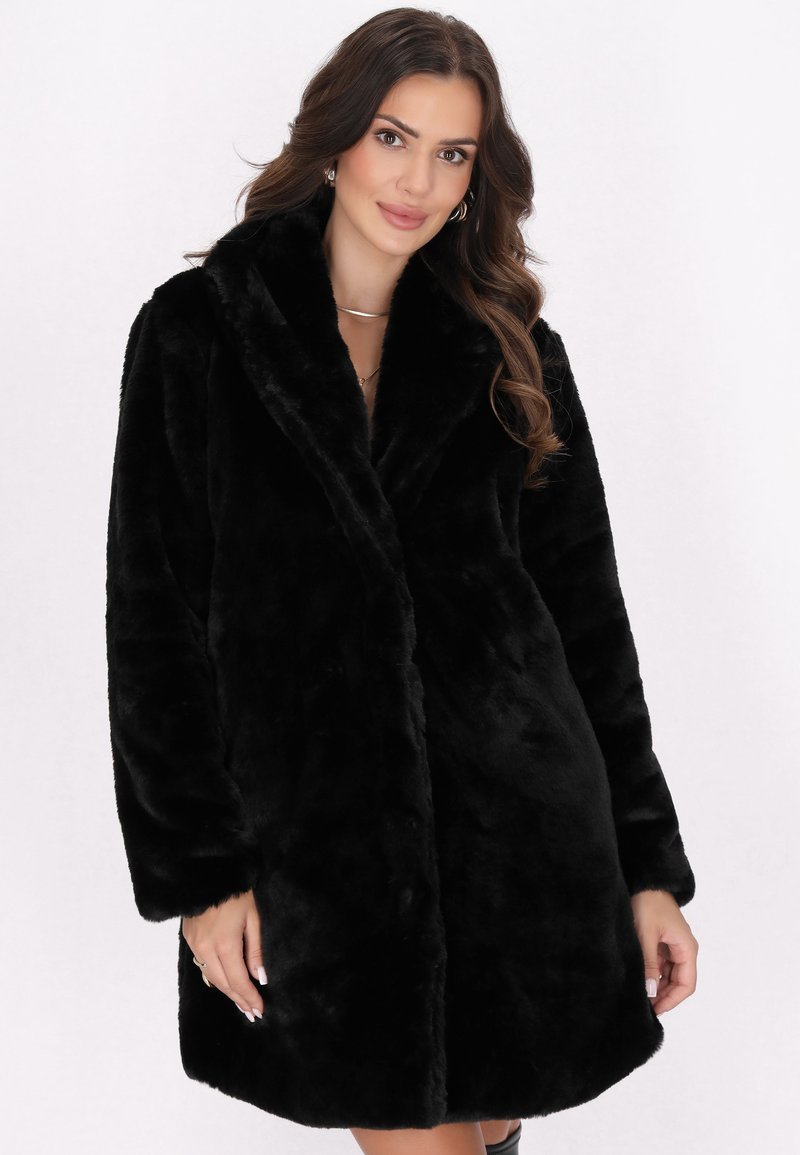 Cappotto in pelliccia sintetica nera con ampio colletto, maniche lunghe e una consistenza morbida. Presenta una vestibilità rilassata e nessuna chiusura visibile.