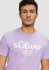 Fialové tričko s krátkým rukávem s bílým logem a nápisem "s.Oliver", kulatý výstřih, lehký materiál, hladká textura.