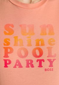 Persikofärgad bomullströja med texten "Sunshine Pool Party" i gradientorange och rosa nyanser, i en fet, lekfull font.