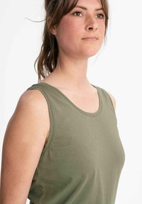 Olijfgroene mouwloze top gemaakt van zachte katoen. Beschikt over een ronde halslijn en een gladde, aansluitende pasvorm zonder zichtbare patronen of accenten.