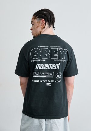 Black cotton t-shirt with graphic text on the back in white. Features oversized fit, round neckline, and short sleeves.
