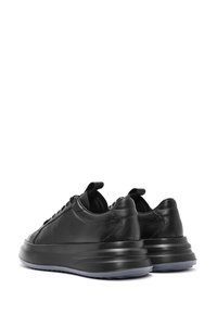 Sneaker in pelle nera con forma arrotondata, dotate di chiusura con lacci, una fodera imbottita e una suola spessa e strutturata.