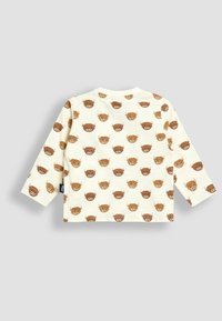 Cremfarbendes Langarmbabyshirt mit wiederholtem Muster von lächelnden braunen Cartoon-Tiergesichtern auf der Vorder- und Rückseite.