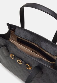 Zwarte handtas met textuur, voorzien van gouden hardware en een ritssluiting. Het interieur is uitgerust met vakken met beige voering en merkopschrift.