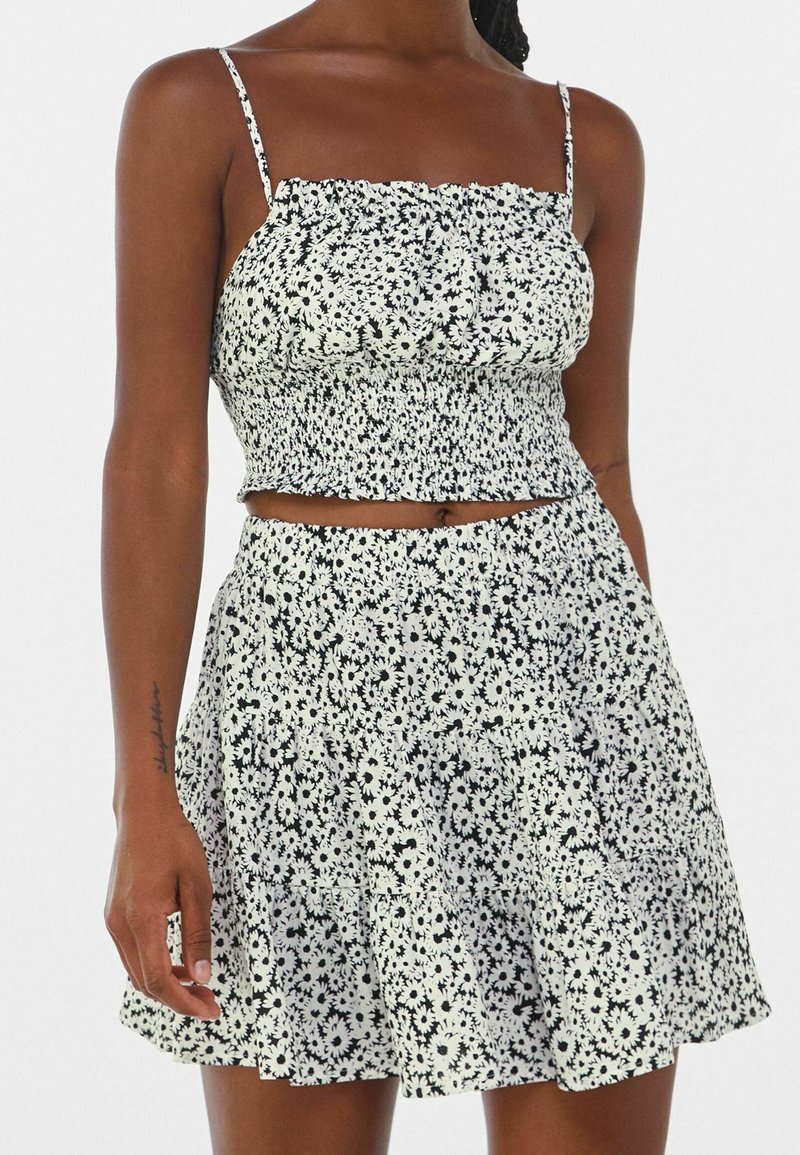 Black and white floral print crop top with smocked design, paired with a matching flared skirt. Both made of lightweight fabric.