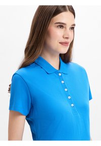 Kurzarm-Polo-Shirt in leuchtendem Blau, aus glattem Baumwollstoff, mit klassischem Kragen, einer Knopfleiste mit fünf Knöpfen und weicher Textur.