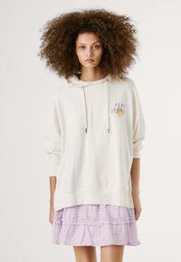 Crème hoodie met een vooropdruk in paars en geel. Gecombineerd met een lichtpaarse, gelaagde, gerimpelde rok. Glad textuur, casual fit.