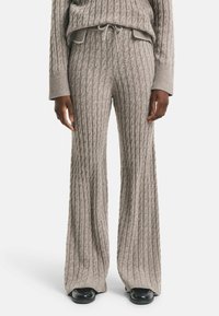 Grijze gebreide lounge-outfit set met gestructureerde kabelpatronen, relaxte wijde broekspijpen en een bijpassende trui met een ribbelkraag.