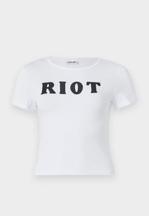 Hvit kortermet t-skjorte med rund hals, med ordet "RIOT" i fete svarte bokstaver på forsiden. Mykt bomullsmateriale.