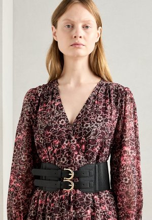 Black double-buckle belt over a floral-patterned, deep red dress with long sleeves and a V-neck. The material is lightweight and textured.