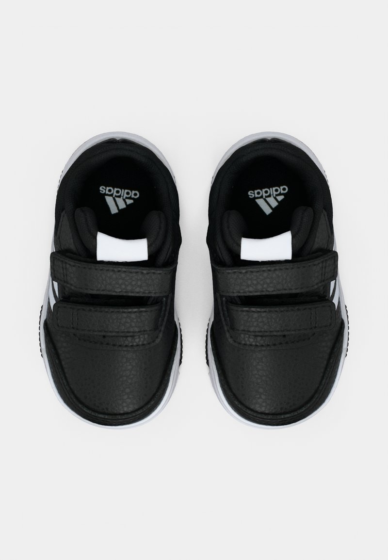 Ein Paar schwarze und weiße Adidas-Kindersneaker mit Klettverschluss, von oben auf einem weißen Hintergrund gezeigt.