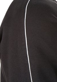 Camicia in cotone nera con finitura texturizzata, caratterizzata da una cucitura bianca a contrasto che corre verticalmente lungo la spalla.