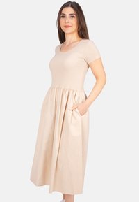 Beiges, knielanges Kleid mit kurzen Ärmeln, einem eng anliegenden Oberteil und einem ausgestellten Rock. Verfügt über Seitentaschen und einen glatten, strukturierten Stoff.