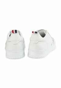 Witte leren sneakers met een gladde textuur, met een ronde neus, platte zool en een hielaccent met een rood, wit en blauw gestreept patroon.