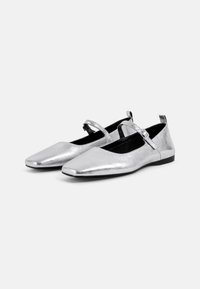 Silver metallic ballet flats with a square toe, ankle strap, and a flat sole. The upper is textured, with a contrasting black interior.