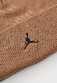 Beanie lavorato a maglia marrone con logo Jumpman ricamato in nero. La consistenza è liscia con un motivo a coste uniforme in tutto il prodotto.