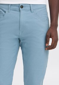 Lichtblauwe denim broek met een gladde textuur, voorzien van een knoopsluiting, voorzakken en een rechte pasvorm.