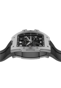 Zilveren roestvrijstalen horloge met een zwart skeleton-dial, rubberen band en grote Arabische cijfers. Beschikt over een verhoogde kast en geventileerde accenten.