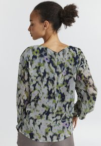 Blusa ampia in tessuto trasparente, con un motivo astratto multicolore in tonalità di verde, blu navy e lavanda. Scollo rotondo sul retro.