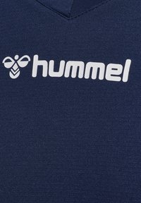 Granatowa koszulka sportowa z dekoltem w serek, wykonana z gładkiego materiału. Na przodzie znajduje się biały logo "hummel" oraz grafika pszczoły.