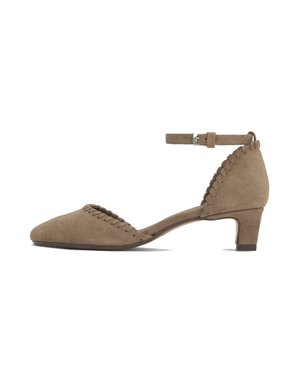 Zapato de ante color topo con tacón bajo, correa en el tobillo y ribete trenzado a lo largo de los bordes de los dedos y el talón, vista lateral sobre fondo blanco.