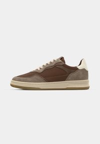 Brown suede sneaker with cream accents, perforated detailing, and beige sole. Features traditional lacing and brand logo on the heel.