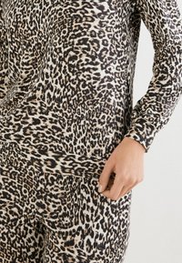 Leopardenmuster Langarmoberteil in Creme, Braun und Schwarz. Weicher Stoff mit markanten Flecken und lässiger Passform, ausgestattet mit einem runden Halsausschnitt.