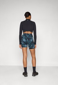 Fekete, hosszú ujjú crop top, fitted fazonnal, párosítva magas derekú, színes virágmintás sorttal. Fekete zoknik és cipők.