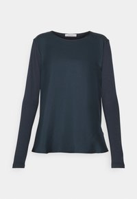 Pitkähihaisen tummansinisen paidan valmistuksessa on käytetty sileää kangasta. Paita on pyöreäkauluksinen ja rento istuvuus on sen ominaisuus, jossa hihoissa on hieman vaaleampi sävy.