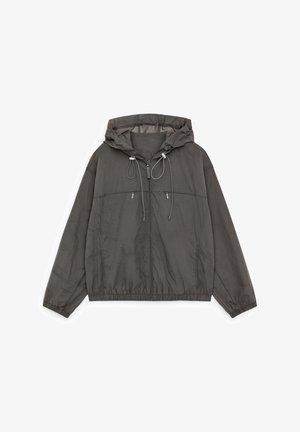 Donkergrijs lichtgewicht jack met capuchon, voorrits, elastische manchetten en zoom, en twee met rits afsluitbare borstzakken met trekkoorden aan de capuchon.