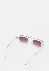 Ochelari de soare cu ramă clară, cu lentile dreptunghiulare în degradé violet. Au o textură netedă și brațe subțiri, transparente.