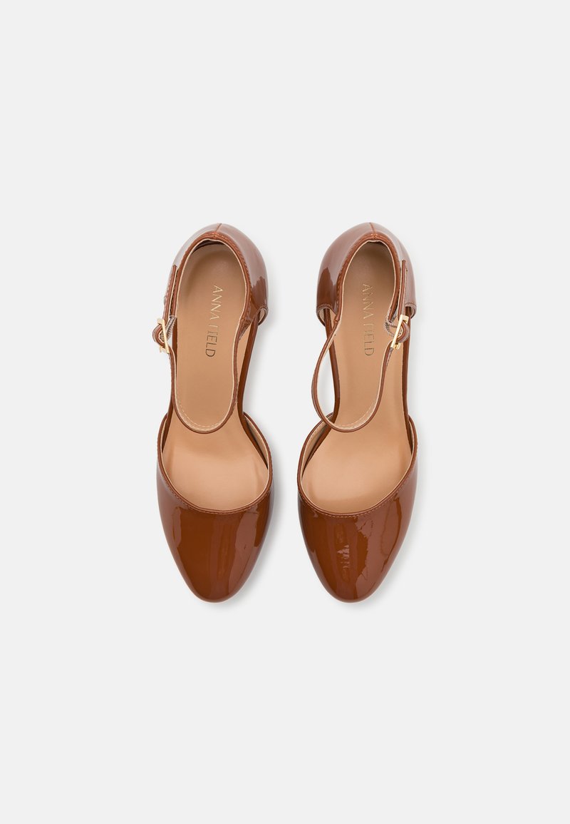 Zapatos slingback de charol marrón con punta afilada y lados abiertos, con un detalle de hebilla en tono dorado y un forro interior suave.