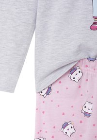 Gray long-sleeve shirt with cartoon graphic on the front, paired with pink pajama bottoms featuring white cat patterns and small hearts.