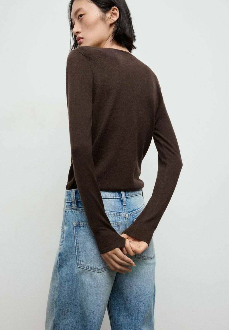 Bruine lange mouwen top met een ronde halslijn, gecombineerd met lichtblauwe wijde jeans. De stof lijkt zacht met een gladde textuur.