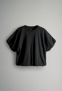 Melnas īsās piedurknes T-krekls, izgatavots no mīksta kokvilnas, ar brīvu piegriezumu, apaļu kakla izgriezumu un savilktu apakšmalu, lai radītu relaksētu siluetu.