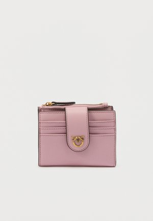 Portefeuille compact en cuir rose avec fermeture à pression, emblème doré en forme d'abeille, six emplacements pour cartes et une poche à monnaie zippée sur le dessus.