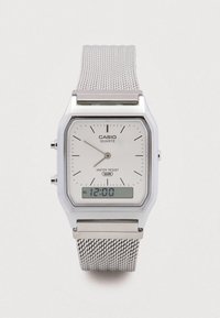 Srebrny zegarek Casio z mechanizmem kwarcowym, z prostokątn�ą tarczą, białą tarczą główną, siateczkowym paskiem, czarnymi markerami minut oraz cyfrowym wyświetlaczem z funkcją alarmu.