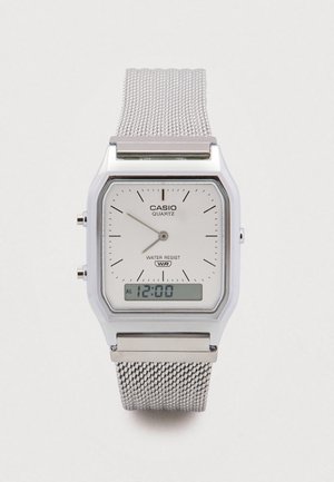 Relógio Casio de quartzo prateado com mostrador retangular, mostrador branco, bracelete tipo malha, marcadores de minutos pretos e ecrã digital com função de alarme.